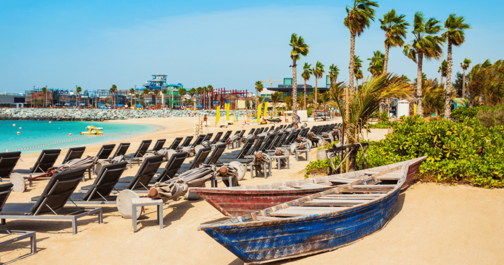 La Mer Dubai - A vibrant beachfront destination with clear blue waters, palm trees, and colorful beach umbrellas. 