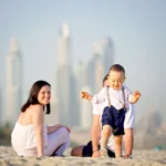 In picture a family couple with walking kid on dubai beach spending vocations and Visit Dubai in Summer: A Comprehensive Guide